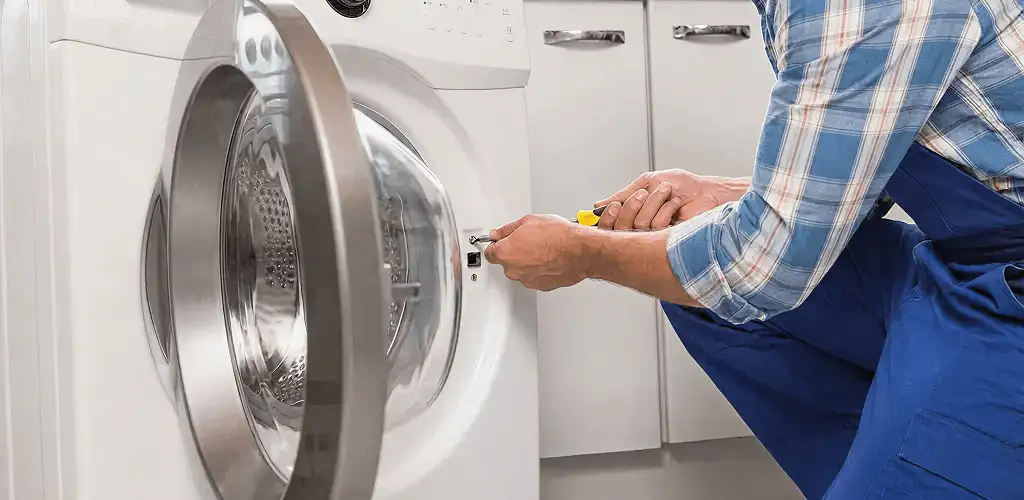 Handyman repairing a clothes dryer and checking electrical connections in Atlanta, GA
