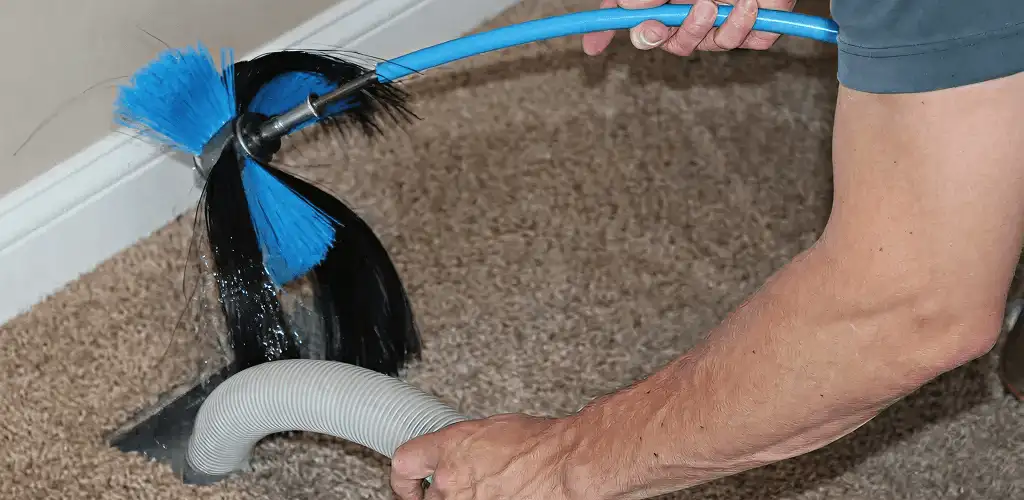 Dryer vent cleaning technician brushing lint from a vent line in Atlanta, GA