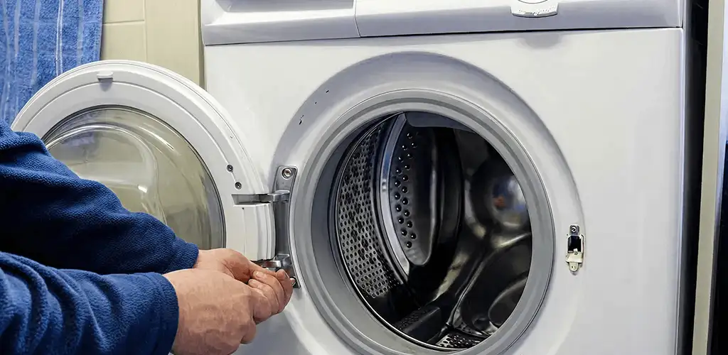 Washing machine repair handyman checking a front-load washer door and latch in Atlanta, GA