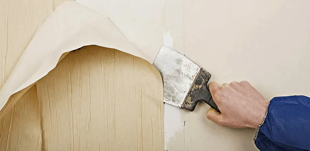 Handyman removing wallpaper with a scraper for wall preparation in Atlanta, GA