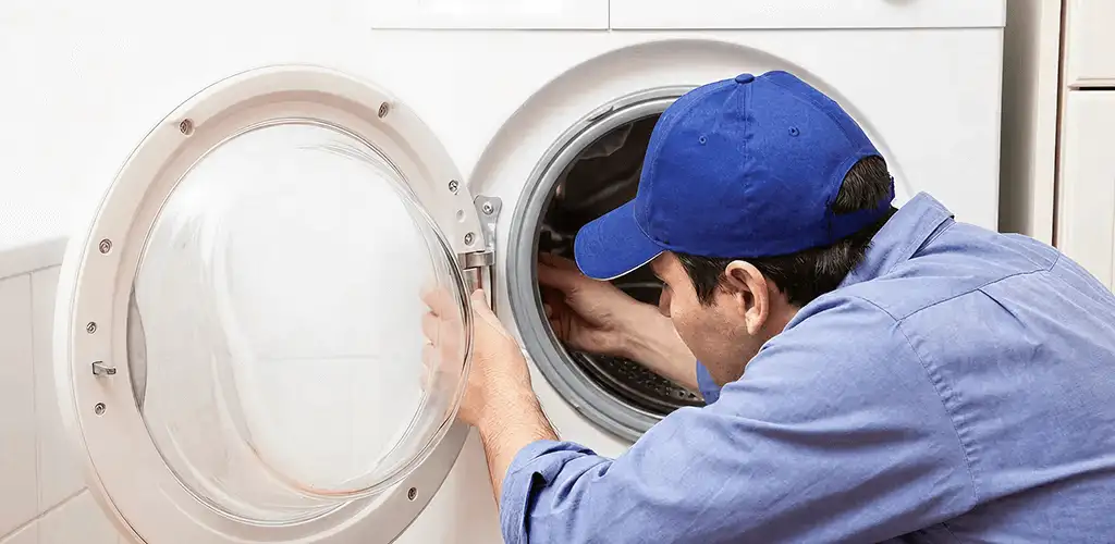 Washing machine repair handyman inspecting a front-load washer drum in Atlanta, GA