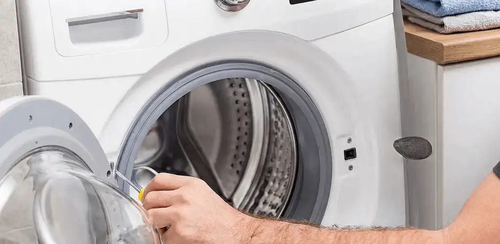 Handyman repairing a front-load washing machine and inspecting the drum in Atlanta, GA
