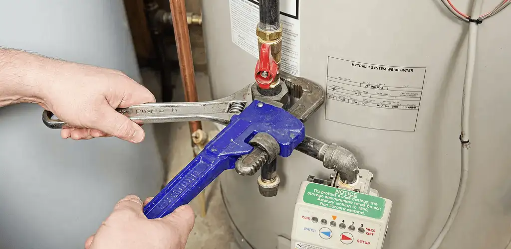 Water heater repair technician tightening the shutoff valve and supply line in Atlanta, GA